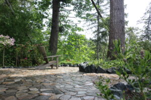 Natural stone patio with basalt boulders, surrounded by a forest, creating a serene and luxurious outdoor living space